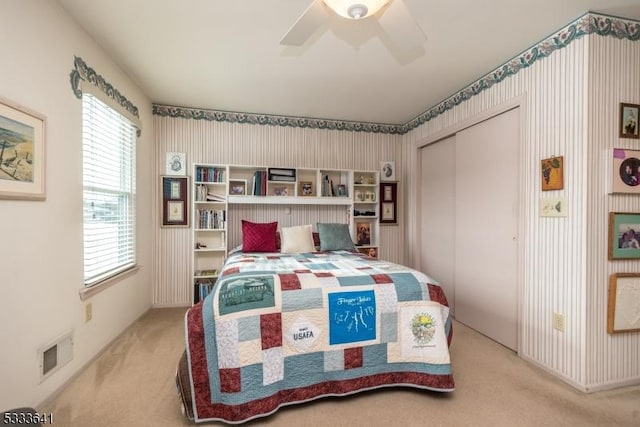 bedroom featuring light carpet, ceiling fan, and a closet