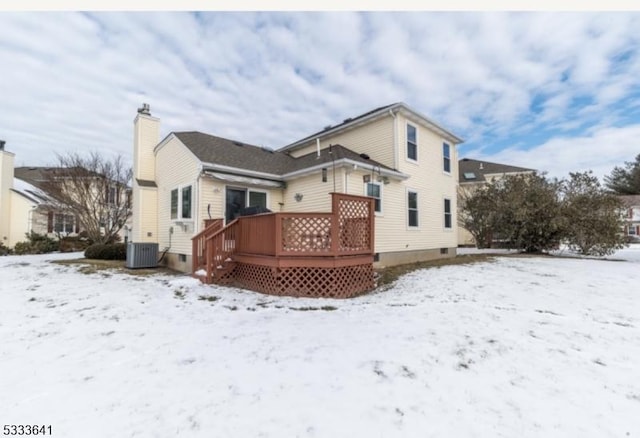 snow covered house with central AC and a deck