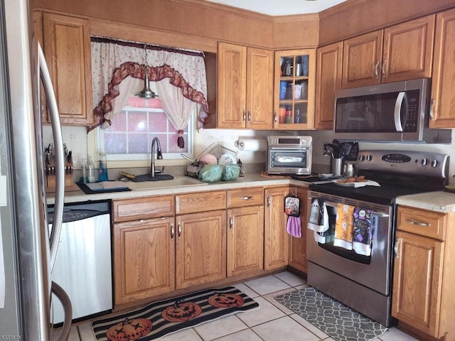 kitchen with appliances with stainless steel finishes, sink, and light tile patterned floors