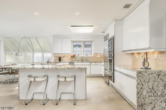 kitchen featuring stainless steel appliances, light stone countertops, and white cabinets