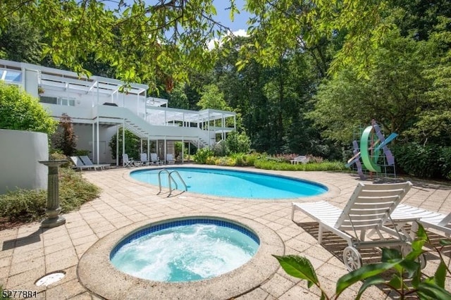 view of swimming pool featuring an in ground hot tub and a patio area