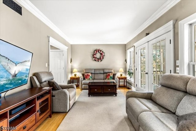 living room with french doors, ornamental molding, and light hardwood / wood-style flooring