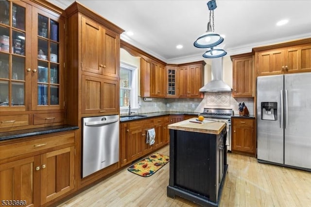 kitchen featuring sink, a center island, pendant lighting, stainless steel appliances, and wall chimney range hood