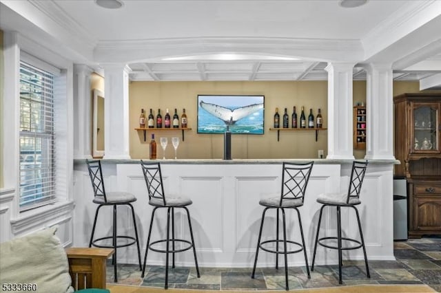 bar with coffered ceiling, crown molding, and decorative columns