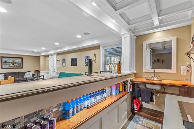 interior space with ornamental molding, coffered ceiling, sink, and beam ceiling