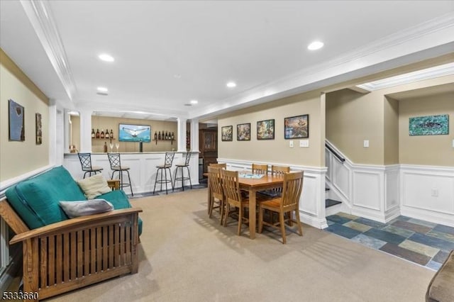 carpeted dining room with crown molding and bar area