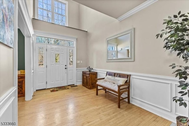 entrance foyer with ornamental molding and light hardwood / wood-style floors