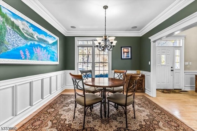 dining room with ornamental molding, a healthy amount of sunlight, a chandelier, and light hardwood / wood-style floors