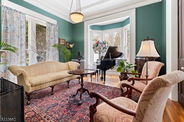 living area with crown molding, plenty of natural light, radiator, and hardwood / wood-style floors