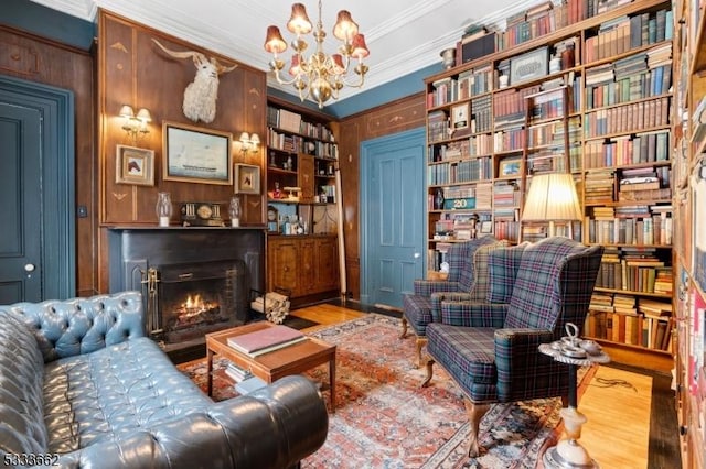 sitting room with crown molding, hardwood / wood-style floors, built in features, and an inviting chandelier