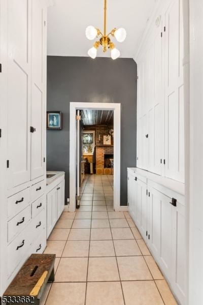 hallway with light tile patterned floors and a chandelier