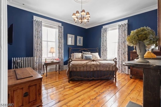 bedroom with crown molding, hardwood / wood-style flooring, and an inviting chandelier