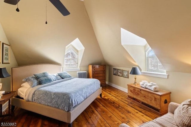 bedroom with dark wood-type flooring, ceiling fan, radiator heating unit, and multiple windows