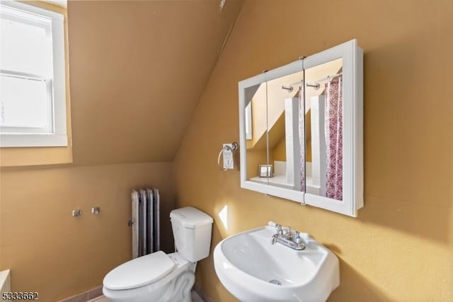 bathroom featuring lofted ceiling, toilet, radiator, and sink