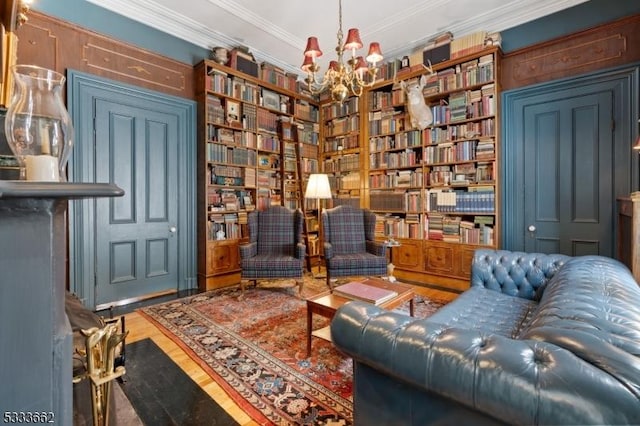 living area featuring crown molding, hardwood / wood-style flooring, and a notable chandelier