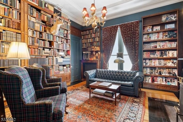 sitting room with an inviting chandelier, ornamental molding, wood-type flooring, and built in shelves