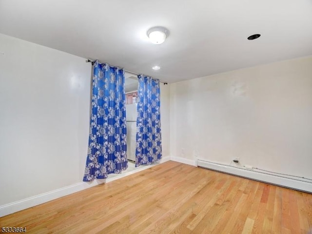 empty room with hardwood / wood-style floors and a baseboard radiator