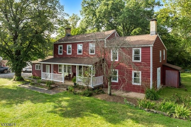 view of front of home featuring covered porch, a front lawn, and a chimney