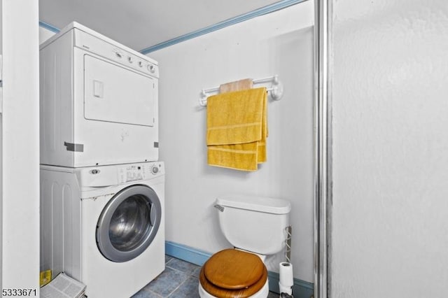 laundry area with laundry area, baseboards, stacked washer / drying machine, and tile patterned floors