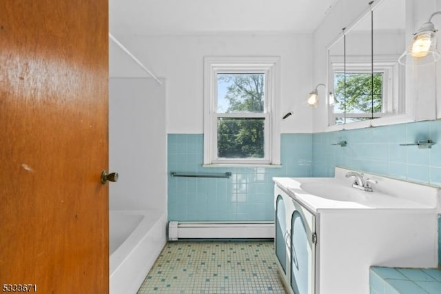 full bathroom featuring wainscoting, a baseboard radiator, vanity, washing machine and dryer, and tile walls