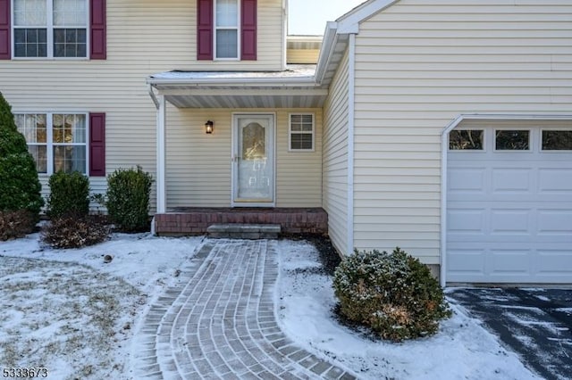 snow covered property entrance with a garage