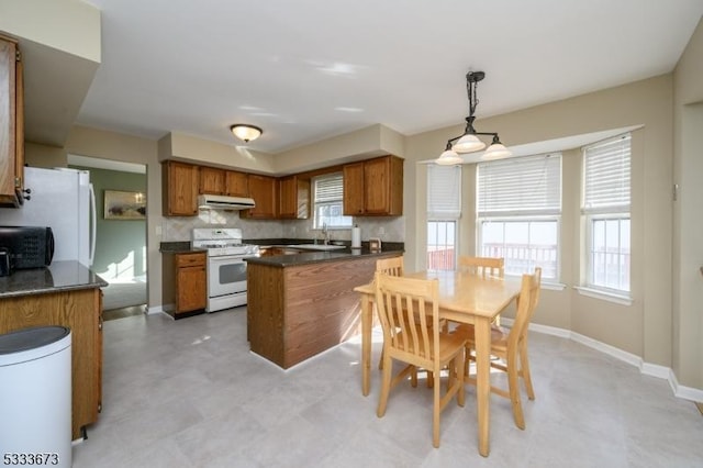 kitchen with white appliances, decorative light fixtures, sink, and decorative backsplash