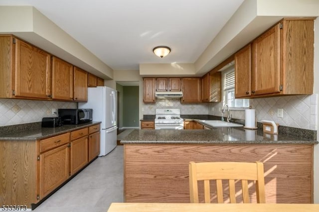 kitchen featuring tasteful backsplash, white appliances, kitchen peninsula, and sink