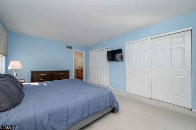 bedroom featuring two closets and light colored carpet