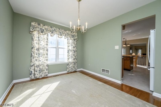 unfurnished room featuring hardwood / wood-style floors and a chandelier