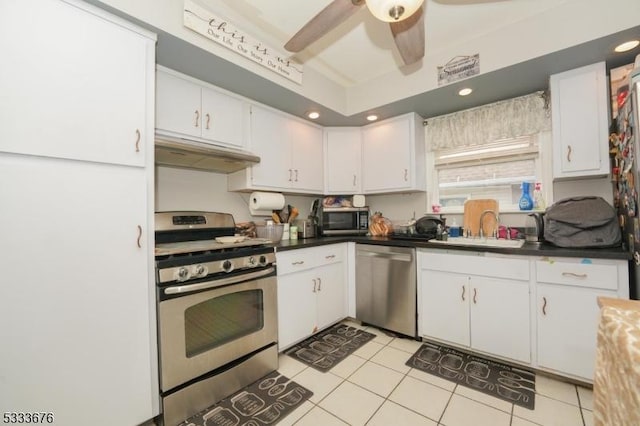 kitchen featuring under cabinet range hood, light tile patterned floors, appliances with stainless steel finishes, white cabinets, and a sink