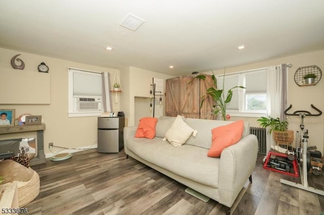 living area featuring recessed lighting, cooling unit, radiator, and wood finished floors