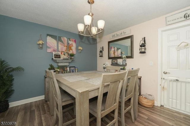 dining room featuring a chandelier, baseboards, and wood finished floors