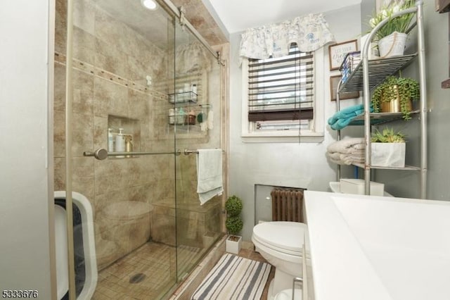 bathroom with a stall shower, toilet, and radiator heating unit