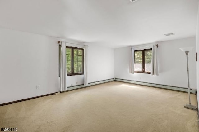 spare room featuring light carpet, a baseboard heating unit, and a healthy amount of sunlight