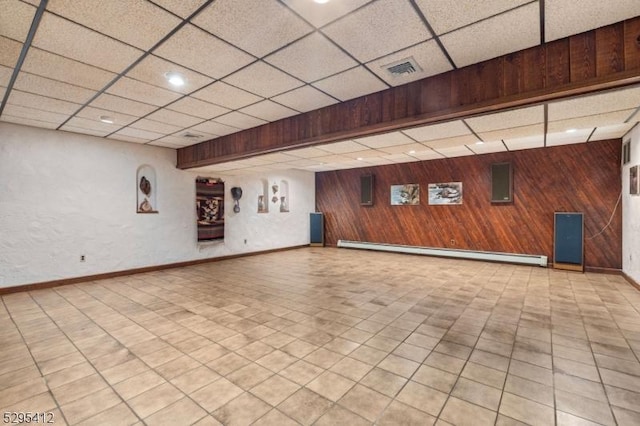 interior space featuring a baseboard radiator, a paneled ceiling, and wood walls