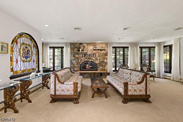 living room with a stone fireplace, plenty of natural light, light colored carpet, and a textured ceiling