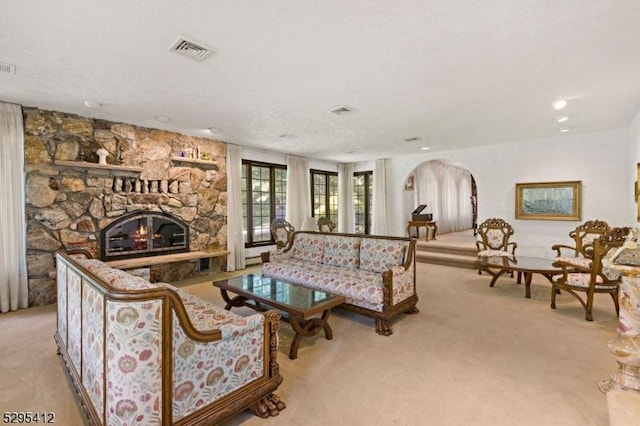 living room featuring a stone fireplace and light carpet