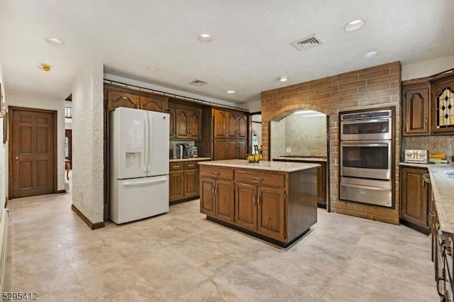 kitchen with a center island, white refrigerator with ice dispenser, and double oven