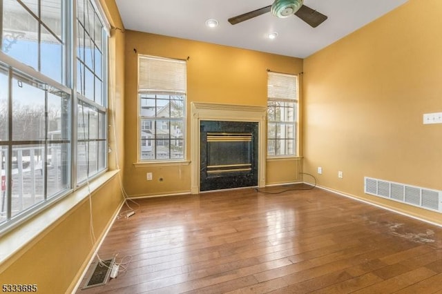 unfurnished living room with hardwood / wood-style floors, a wealth of natural light, and ceiling fan