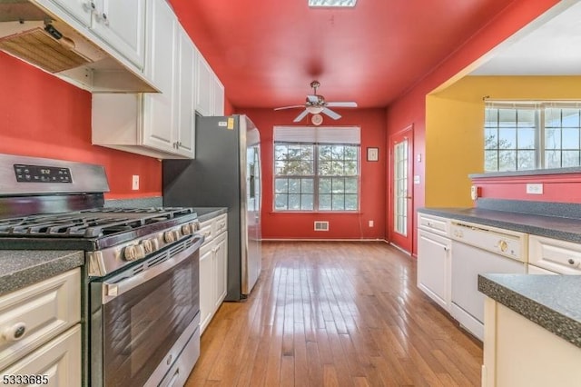 kitchen with stainless steel gas stove, white dishwasher, white cabinets, a healthy amount of sunlight, and light hardwood / wood-style floors