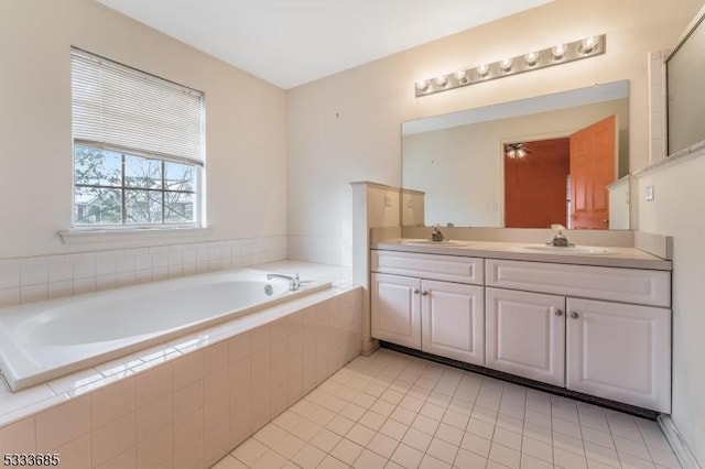 bathroom with tiled tub, tile patterned floors, and vanity