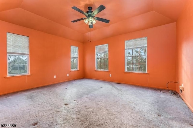 carpeted spare room with ceiling fan, a tray ceiling, and a healthy amount of sunlight