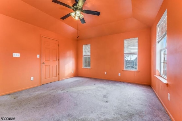 carpeted empty room featuring ceiling fan, lofted ceiling, and a tray ceiling