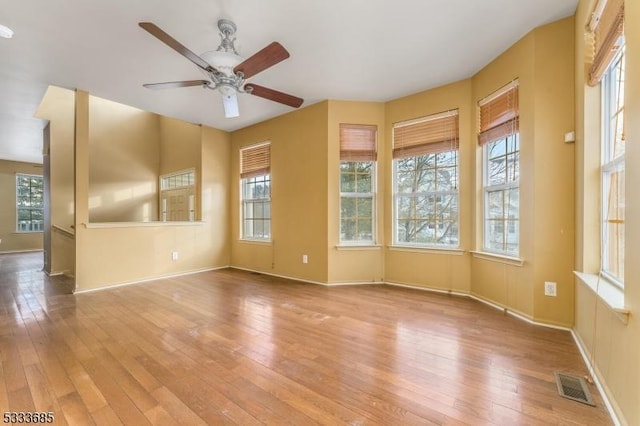 spare room featuring ceiling fan, light hardwood / wood-style flooring, and a healthy amount of sunlight