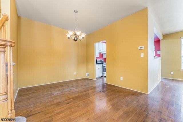 spare room with wood-type flooring and an inviting chandelier