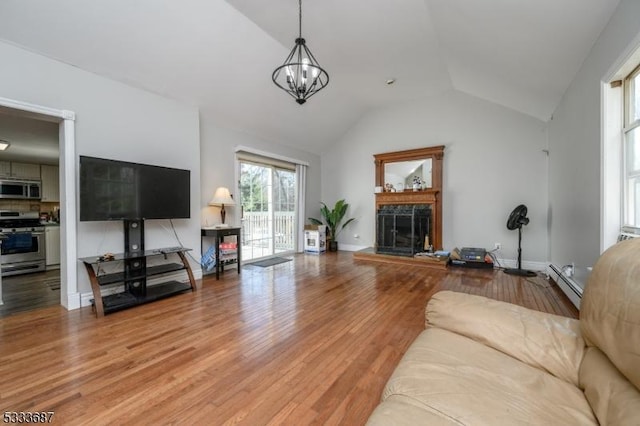 living room with an inviting chandelier, a baseboard heating unit, vaulted ceiling, and hardwood / wood-style floors