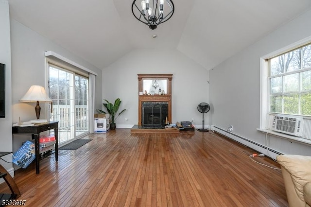 interior space featuring lofted ceiling, baseboard heating, cooling unit, wood-type flooring, and a chandelier