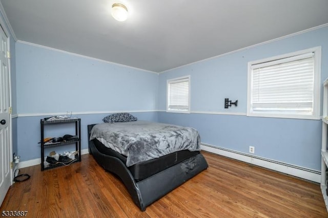 bedroom featuring ornamental molding, hardwood / wood-style floors, and a baseboard heating unit