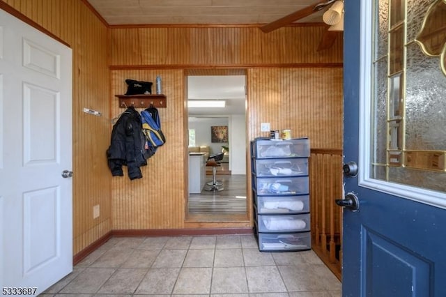 doorway to outside with wooden walls, light tile patterned floors, and ceiling fan