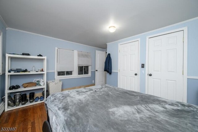 bedroom with crown molding, multiple closets, and dark hardwood / wood-style flooring